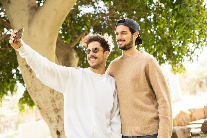 short and tall men taking selfie at the park